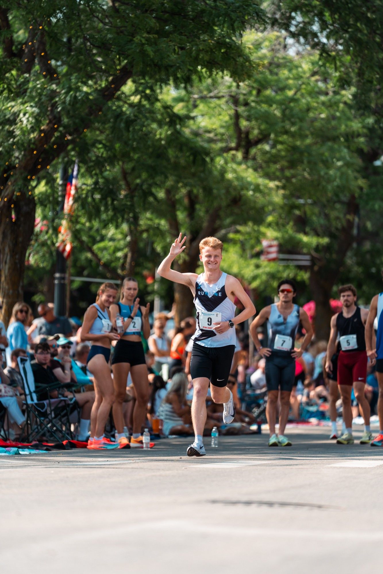 Head coach Henry Johnson waving to the crowd at a road mile in the Runline singlet