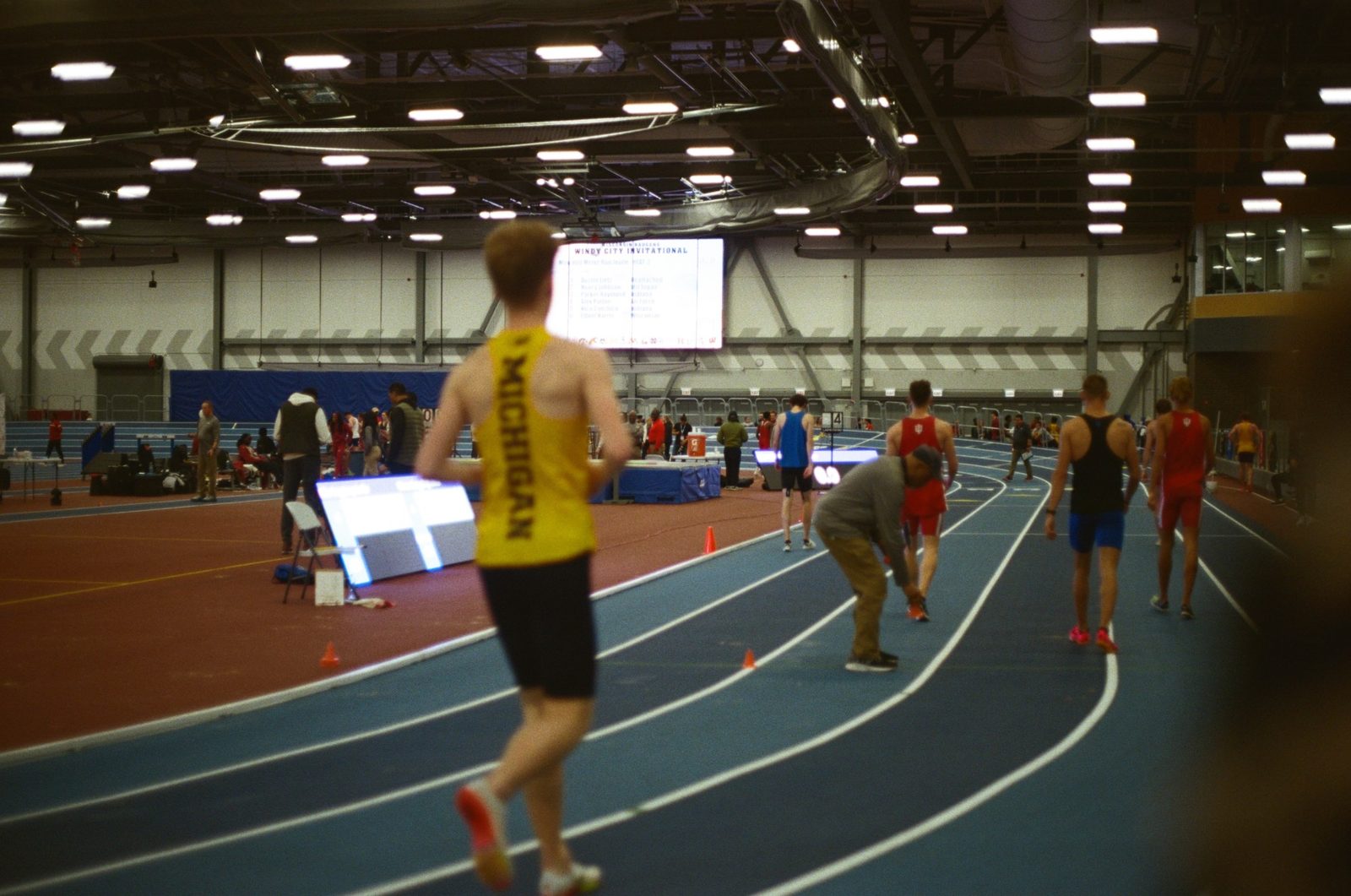 Runners on the banked track at an indoor invitational, shot on film