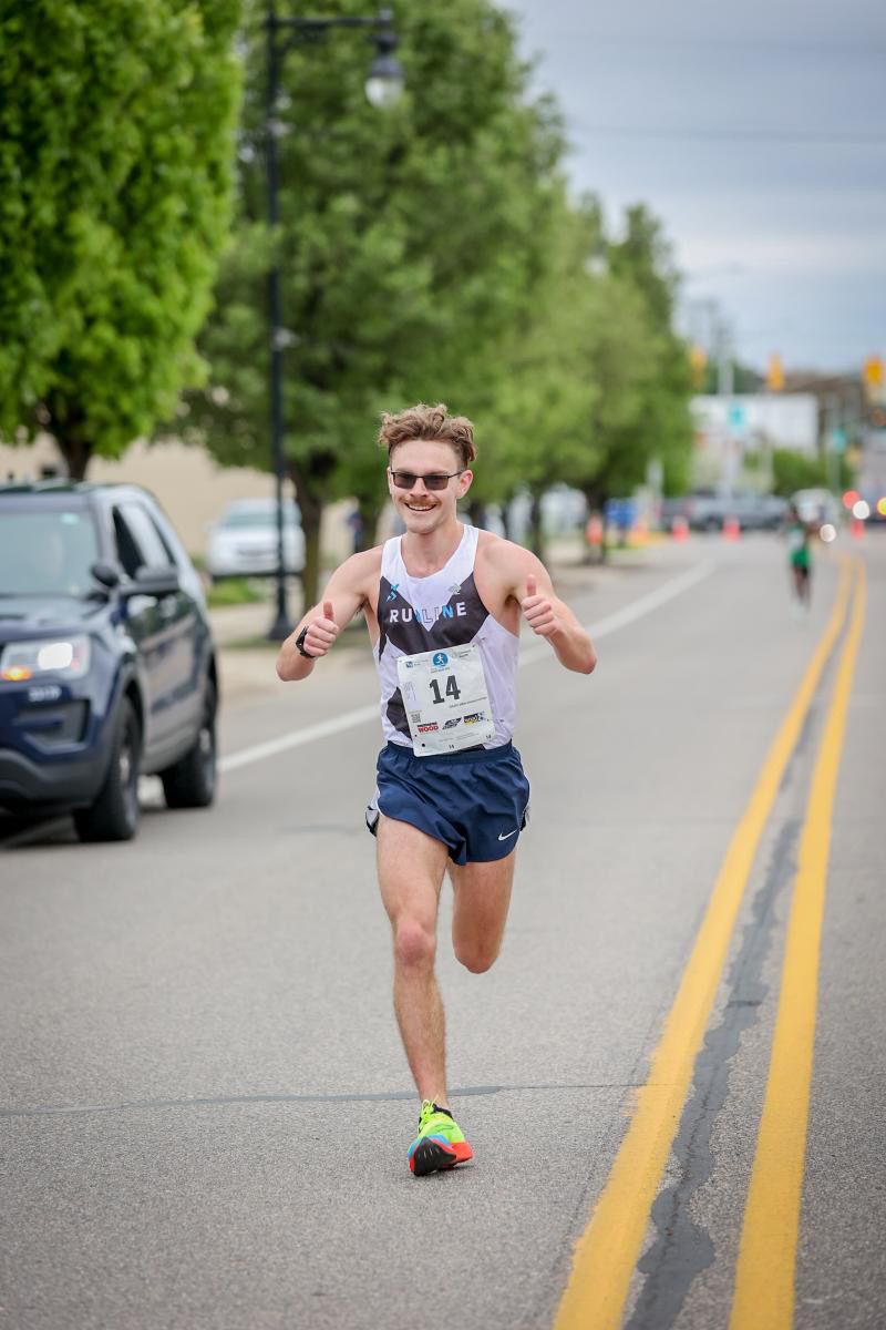 A Runline athlete giving two thumbs up mid-race on a road course